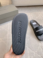 Rubber outsole of black slide sandal with embossed logo tread pattern