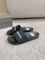 Black slide sandals with cross strap and white logo lettering on the upper