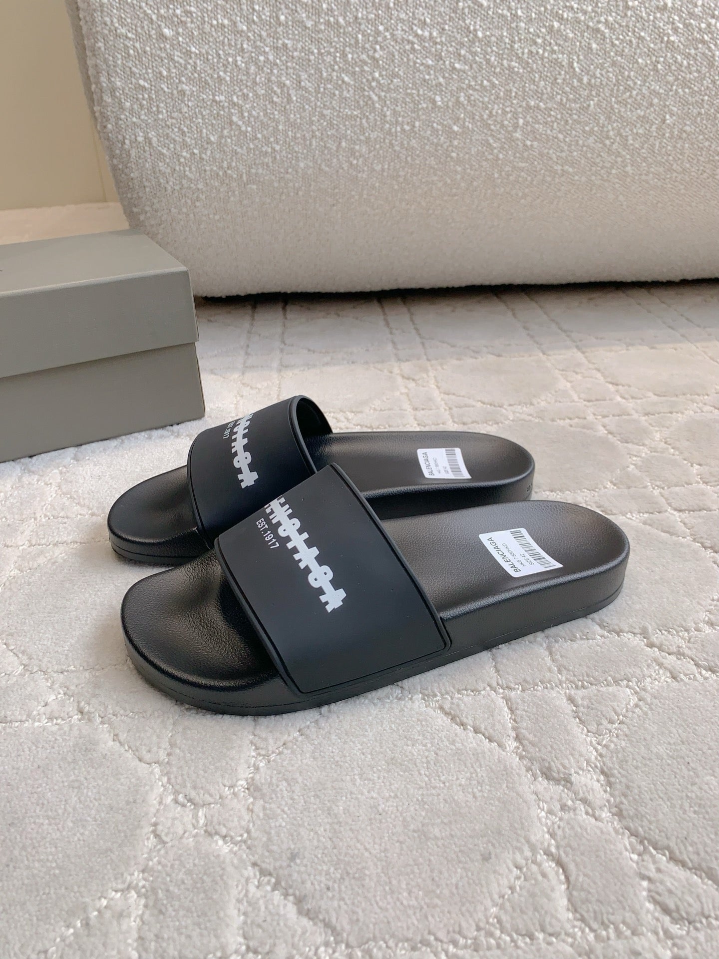 Black slide sandals with cross strap and white logo lettering on the upper