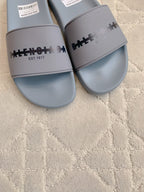 Light blue slide sandals close-up of logo strap and footbed