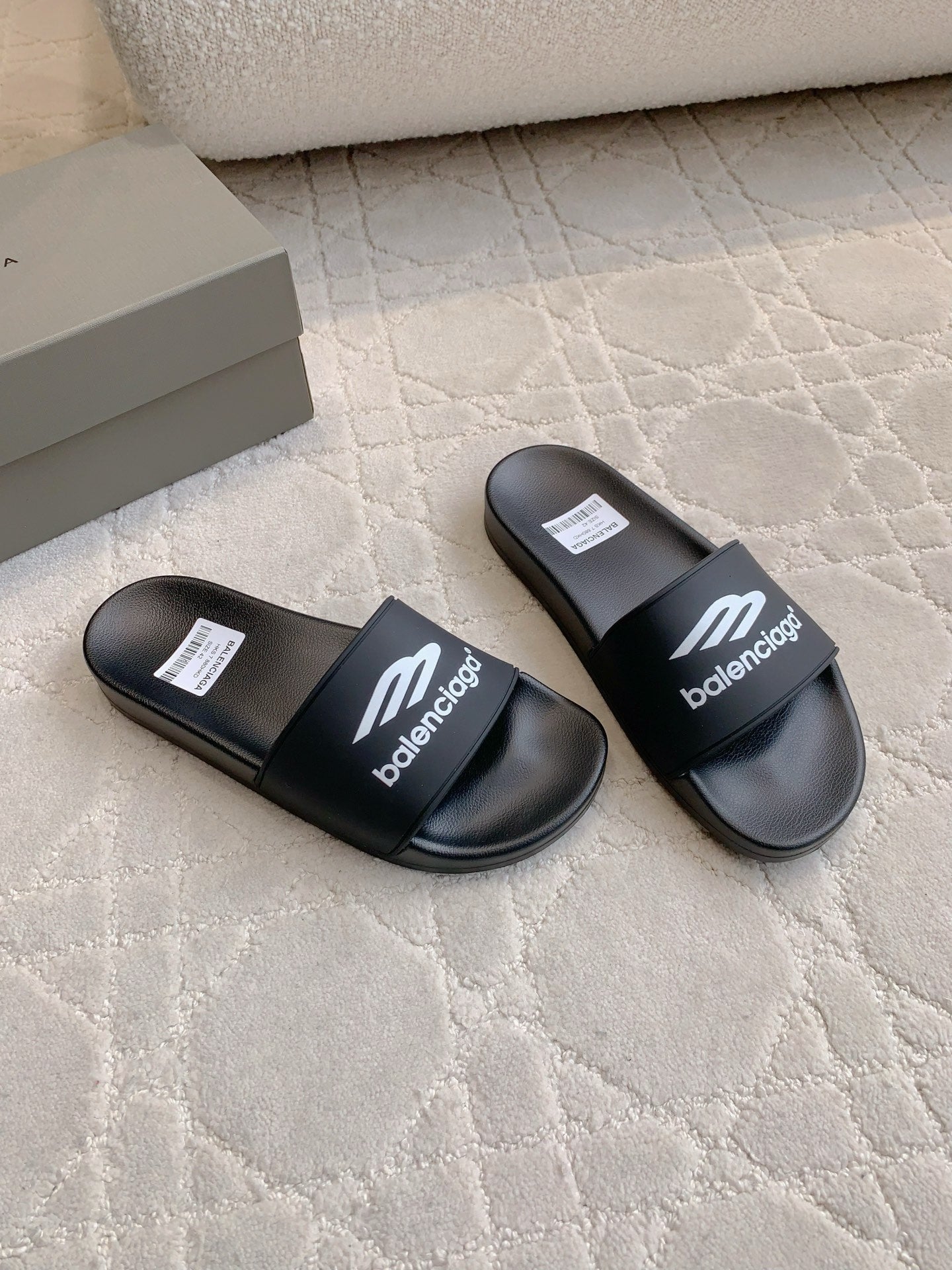 Balenciaga black slide sandals, side view of two sandals with logo straps