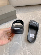 Balenciaga black slide sandal held in hand, open toe and logo print on sole