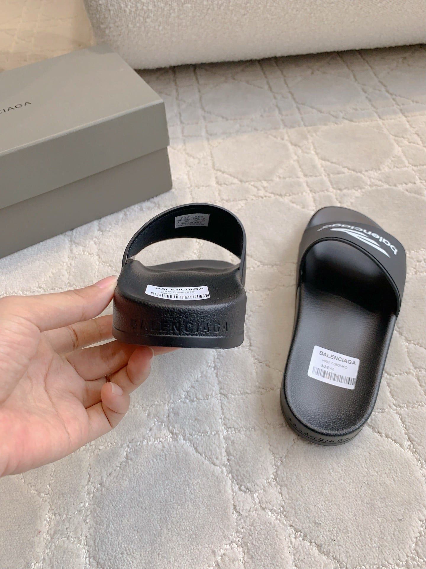 Balenciaga black slide sandal held in hand, open toe and logo print on sole