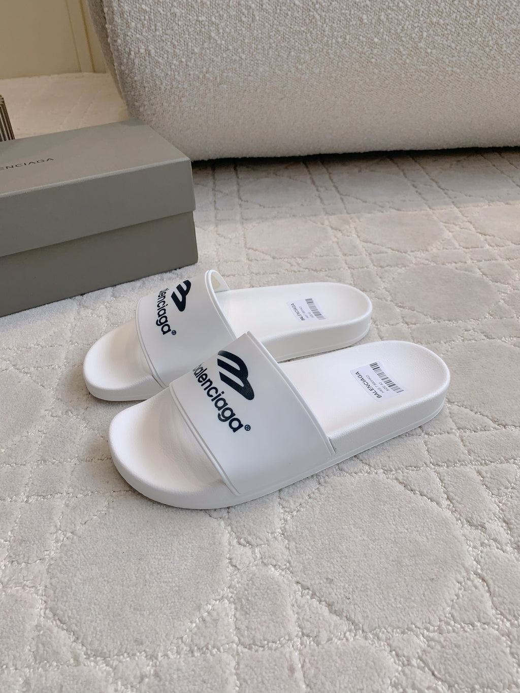 White Balenciaga slide sandals with wide strap and “balenciaga” logo