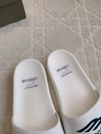 White Balenciaga slide sandals with smooth toe caps and barcode label details