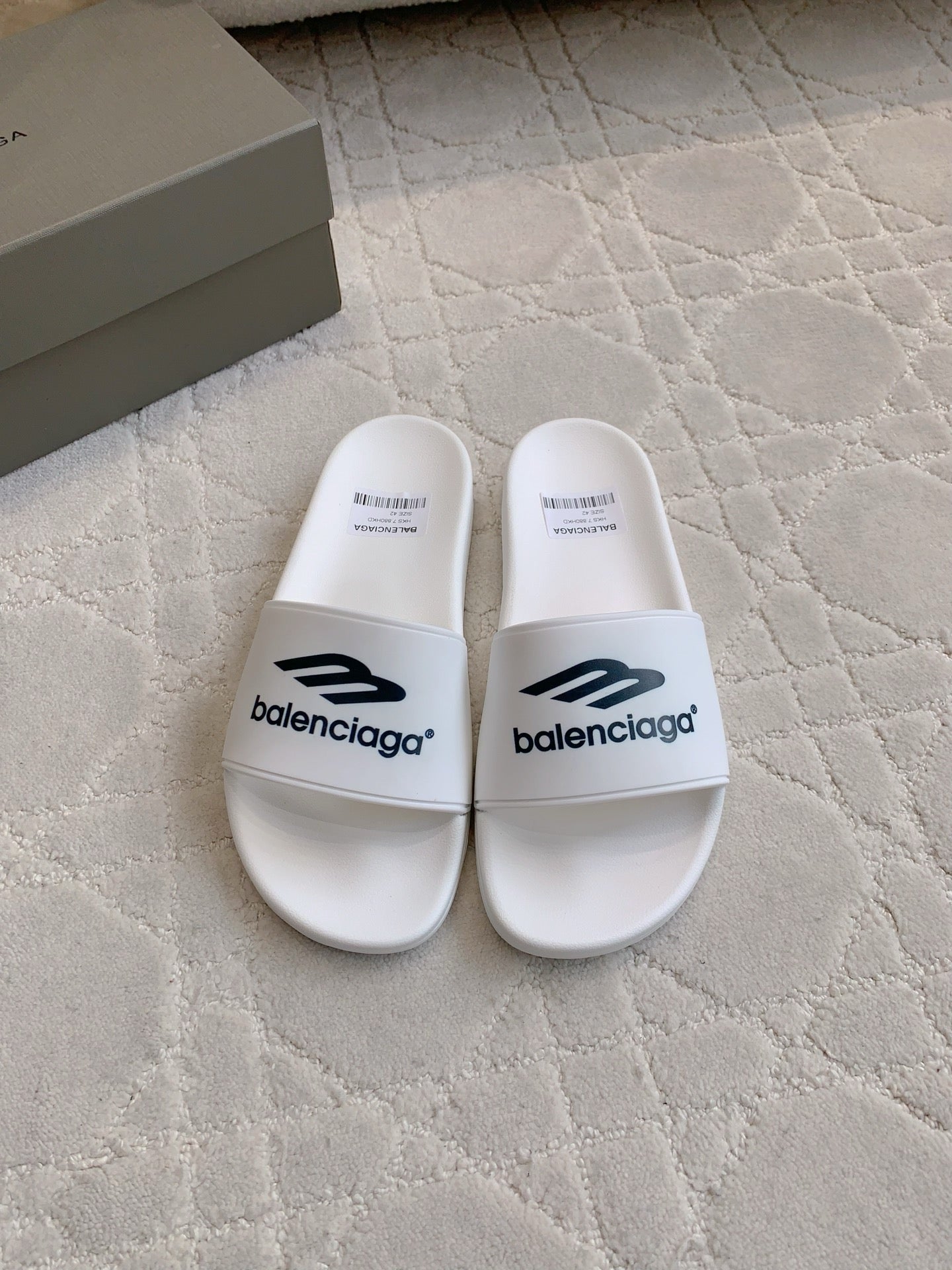 White Balenciaga slide sandals with “balenciaga” logo on the straps