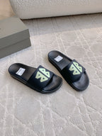 Balenciaga black slide sandals with green logo patches, side view