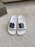 White Balenciaga slide sandals with black logo straps, front view.