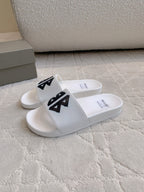 White Balenciaga slide sandals with black logo straps, side angle.