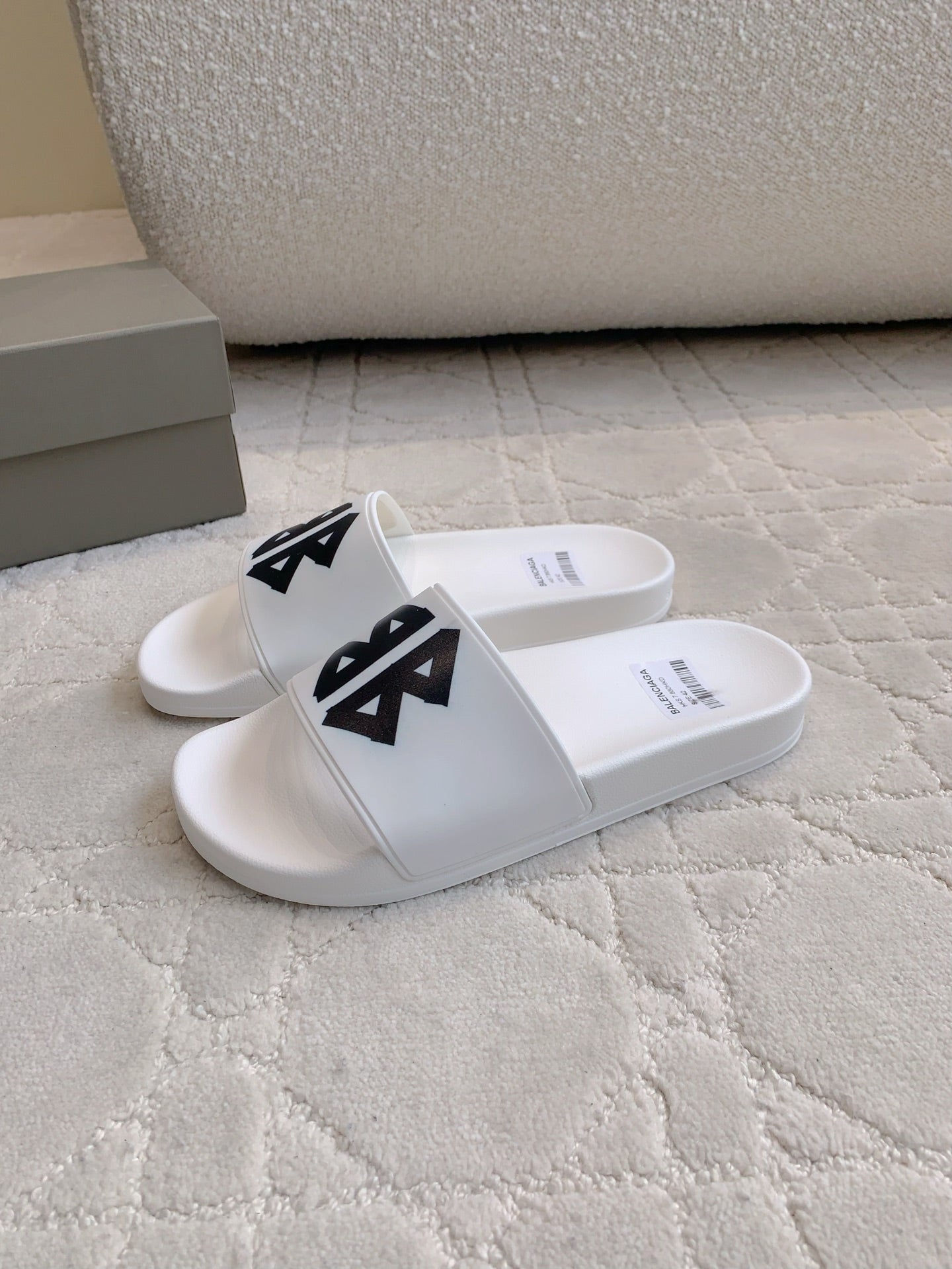 White Balenciaga slide sandals with black logo straps, side angle.