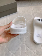 White Balenciaga slide sandal heel, hand-held; embossed Balenciaga logo.