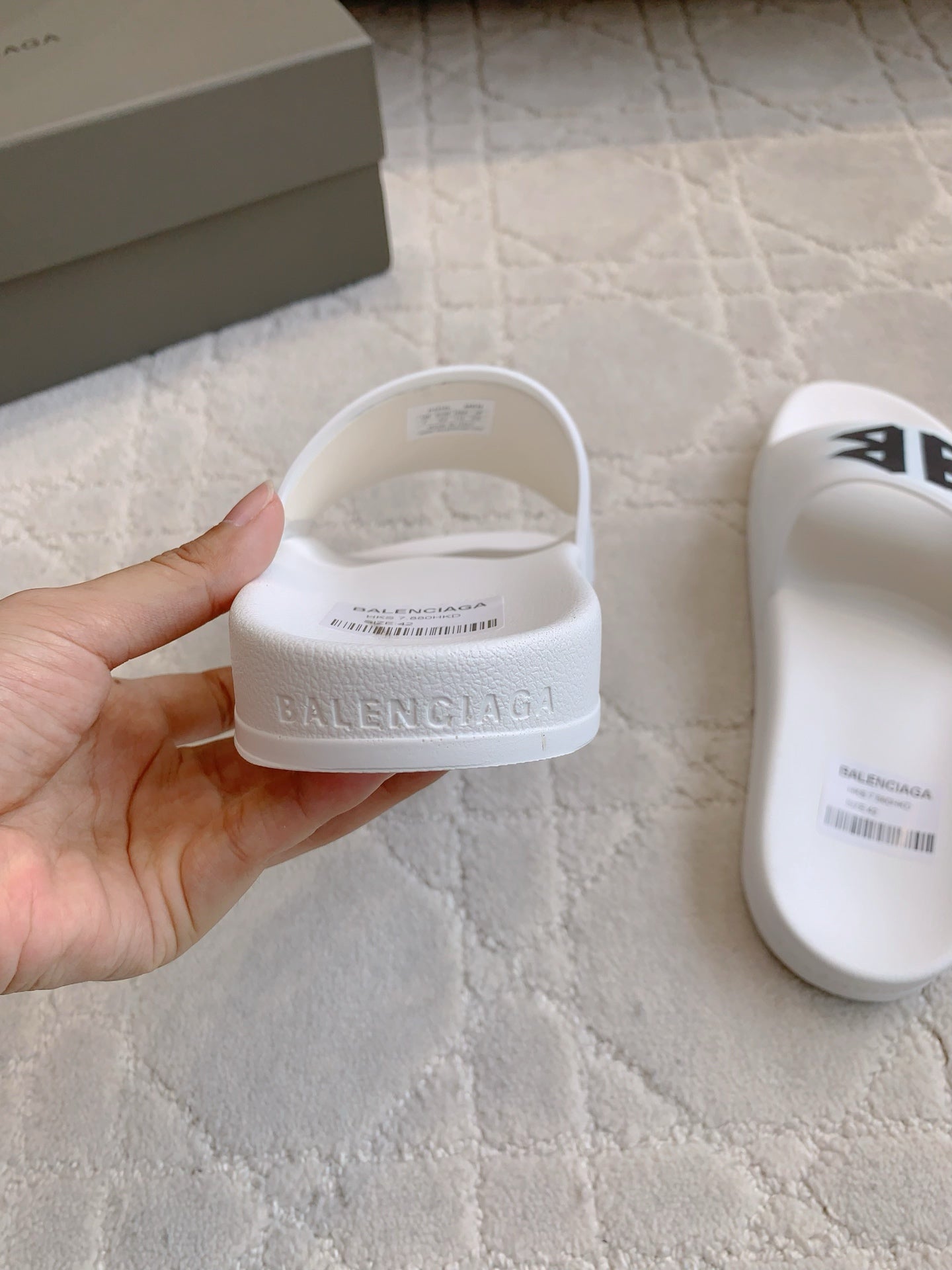 White Balenciaga slide sandal heel, hand-held; embossed Balenciaga logo.