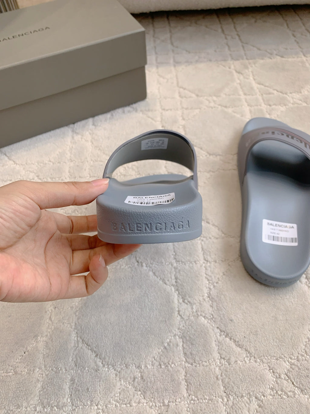 Balenciaga slide sandal held in hand, light blue-gray upper with logo strap