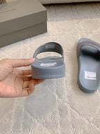 Balenciaga slide sandal held in hand, light blue-gray upper with logo strap
