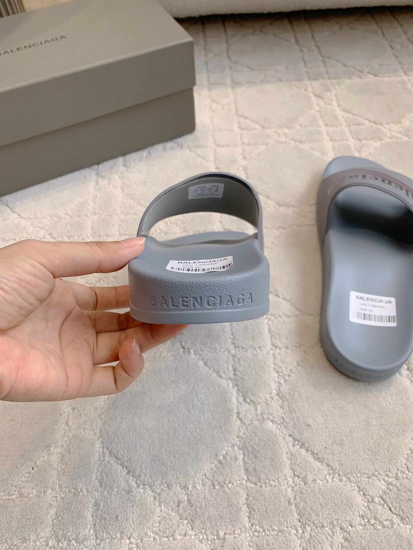 Balenciaga slide sandal held in hand, light blue-gray upper with logo strap