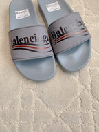 Balenciaga slide sandals close-up, light blue-gray straps with Balenciaga logo