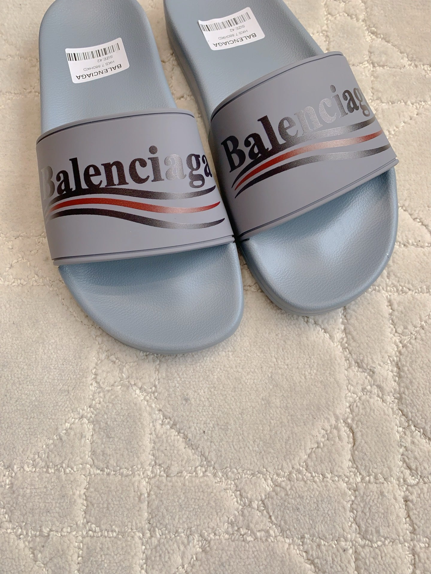 Balenciaga slide sandals close-up, light blue-gray straps with Balenciaga logo