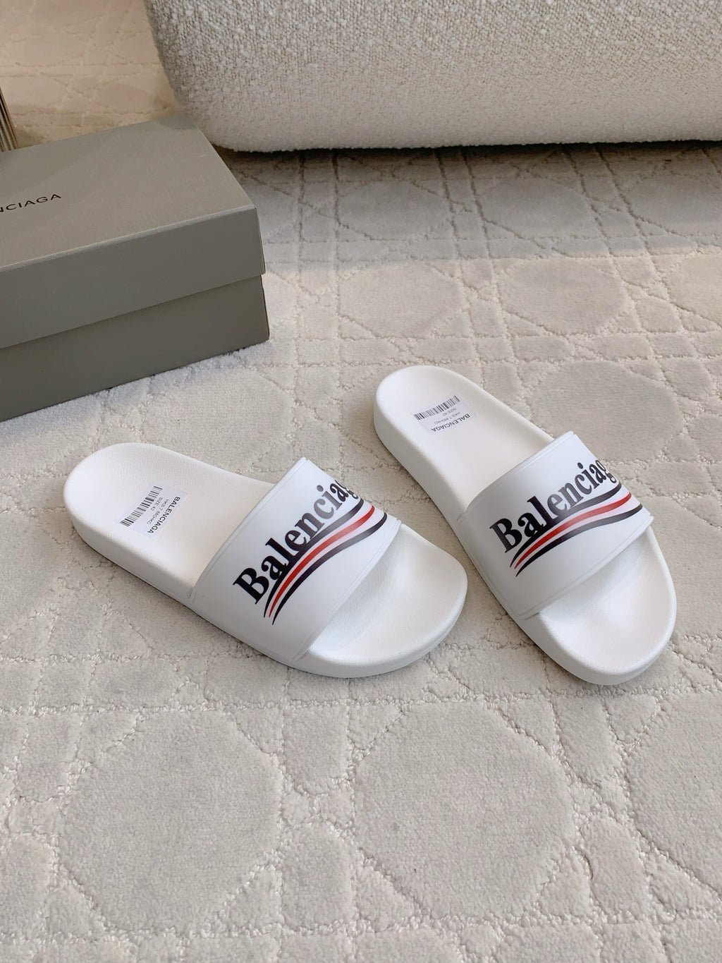 White slide sandals in side view with Balenciaga logo across strap