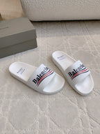 White slide sandals in side view with Balenciaga logo across strap