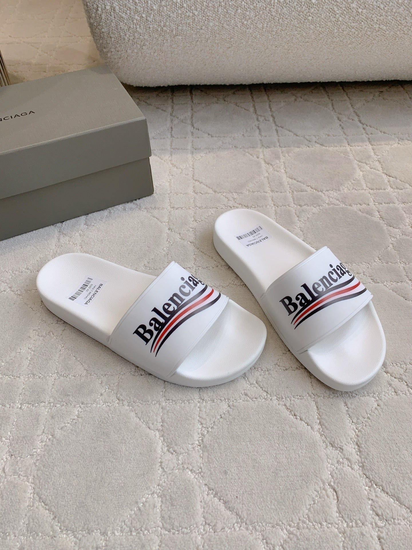 White slide sandals in side view with Balenciaga logo across strap