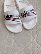 White slide sandals, close-up of Balenciaga logo strap