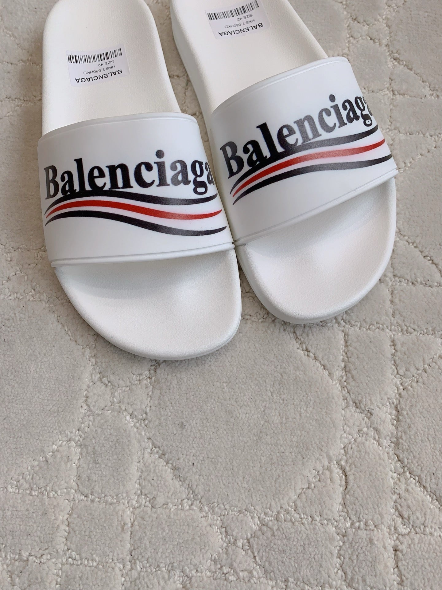 White slide sandals, close-up of Balenciaga logo strap