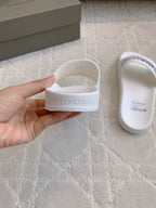 White slide sandals heel, hand holding pair with Balenciaga logo