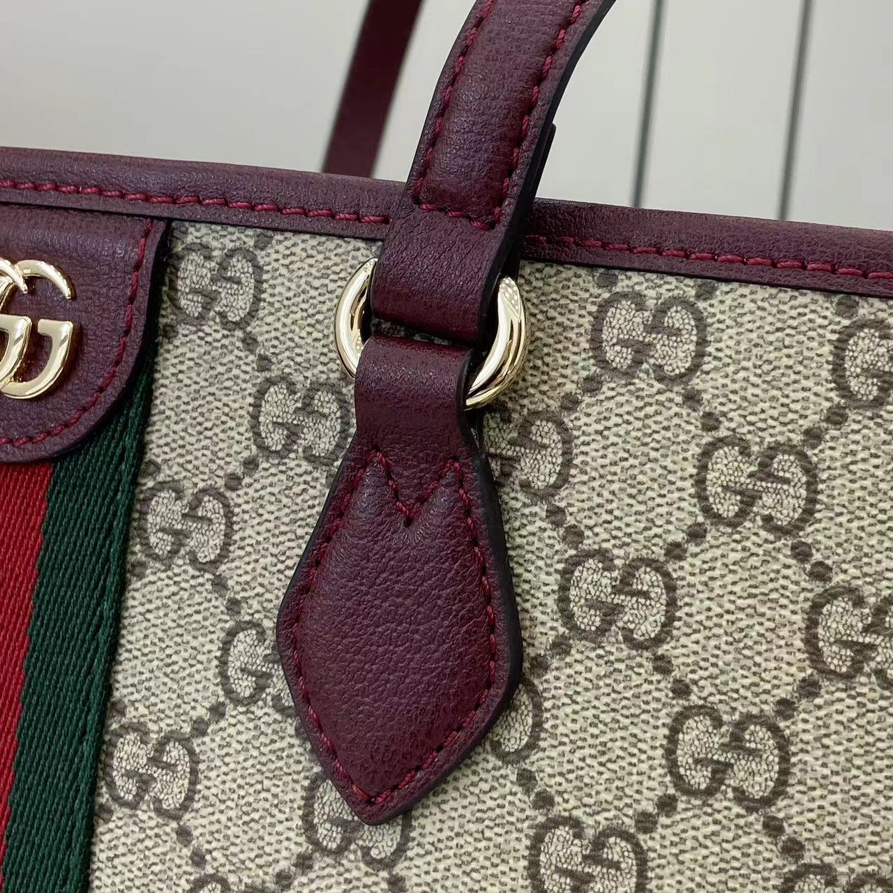 Gucci bag close-up: GG canvas with burgundy leather strap and trim