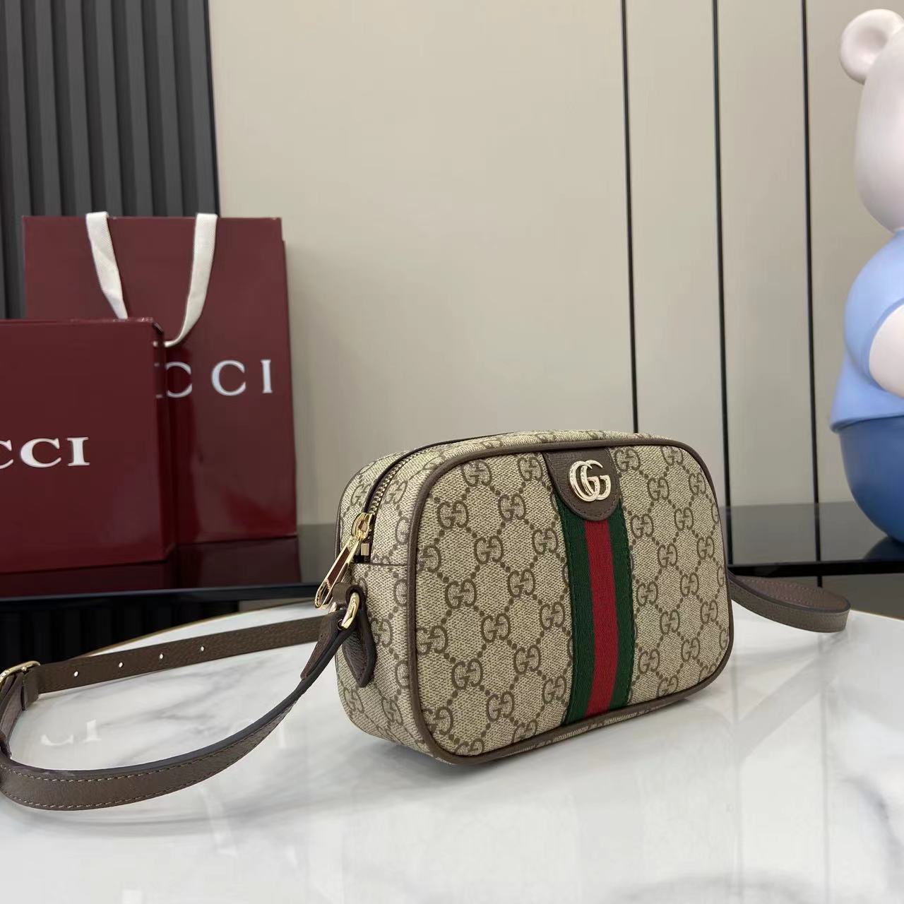 Gucci crossbody bag with beige GG canvas, stripe detail, and adjustable leather strap