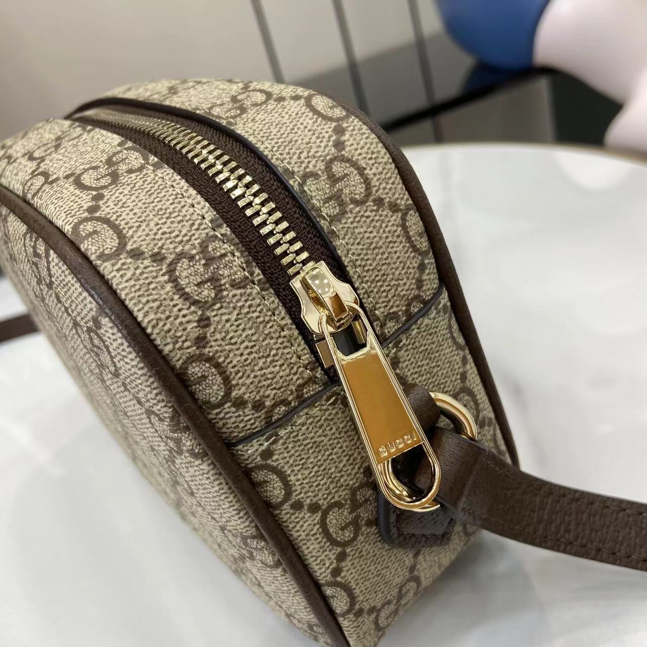 Gucci crossbody bag zipper hardware on beige GG canvas with brown trim