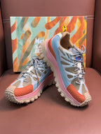 Two-tone sneakers with light blue uppers, pink sole, and chunky studded tread