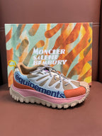 Low-top sneakers with white uppers, orange and pink trim, and spiked outsole