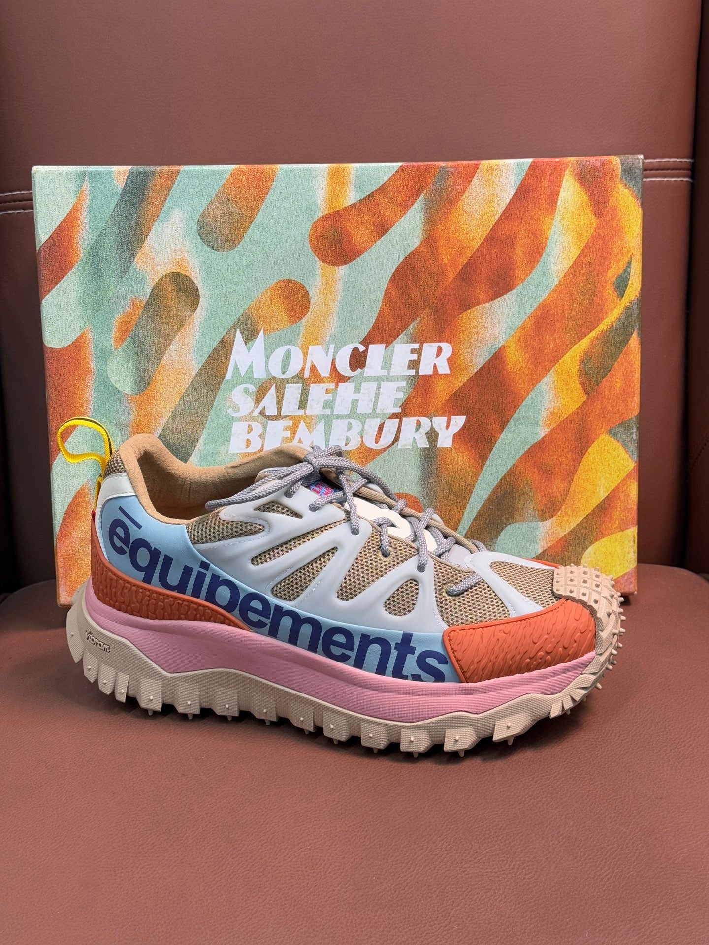 Low-top sneakers with white uppers, orange and pink trim, and spiked outsole