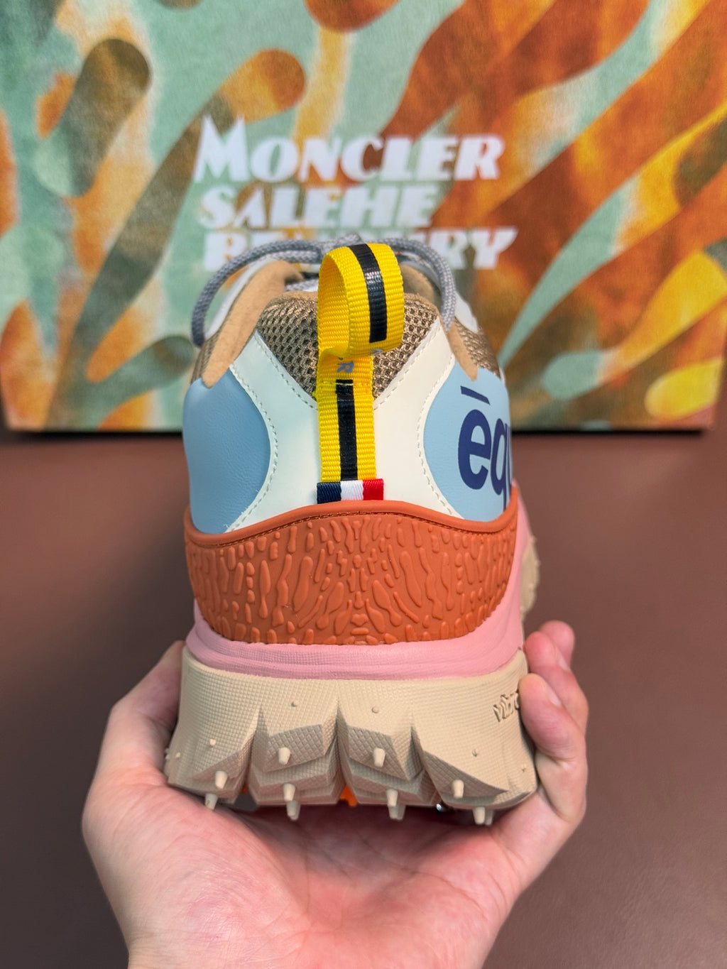 Heel view of light blue and orange sneakers with pink midsole and tread