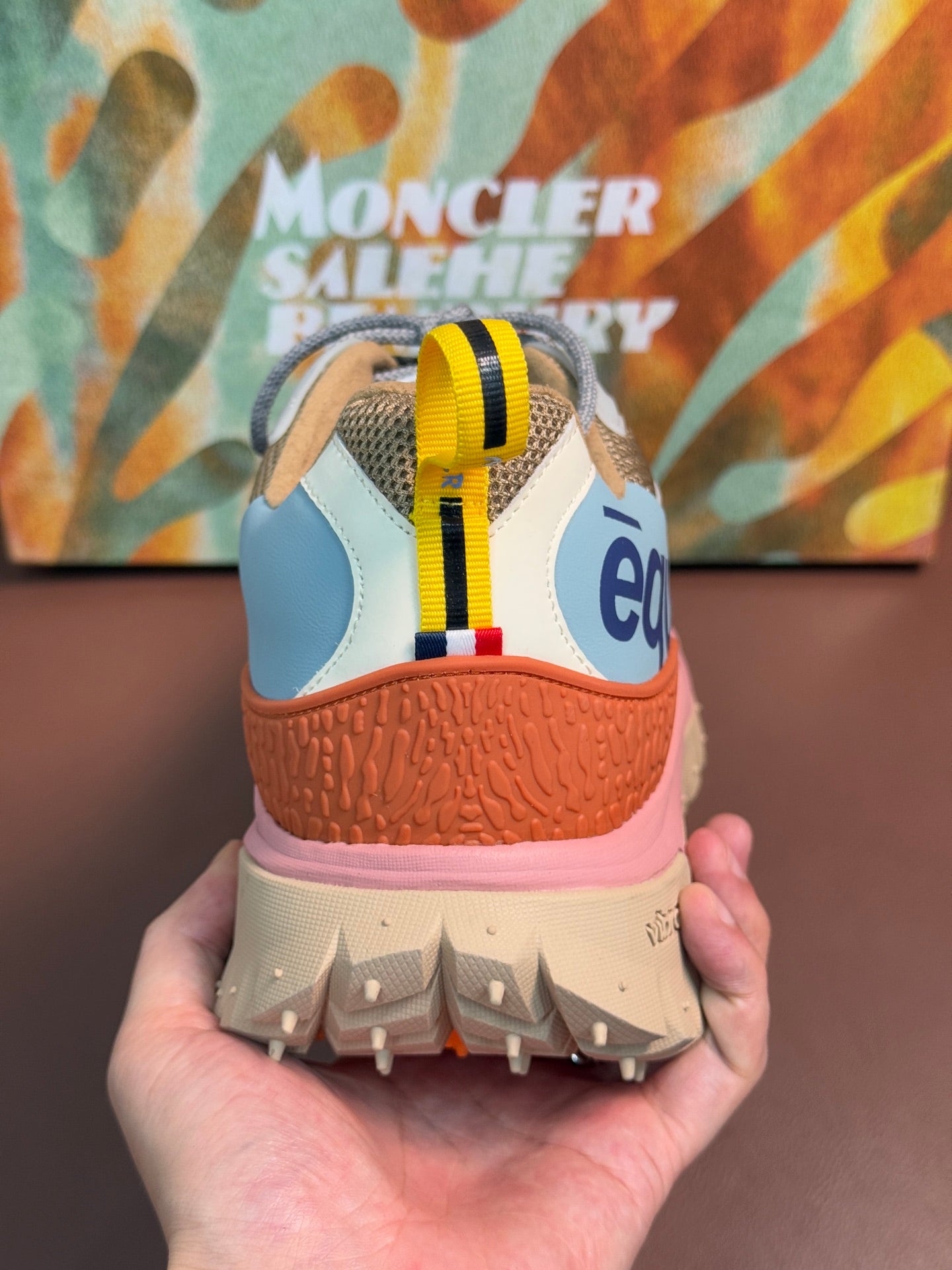 Heel view of light blue and orange sneakers with pink midsole and tread