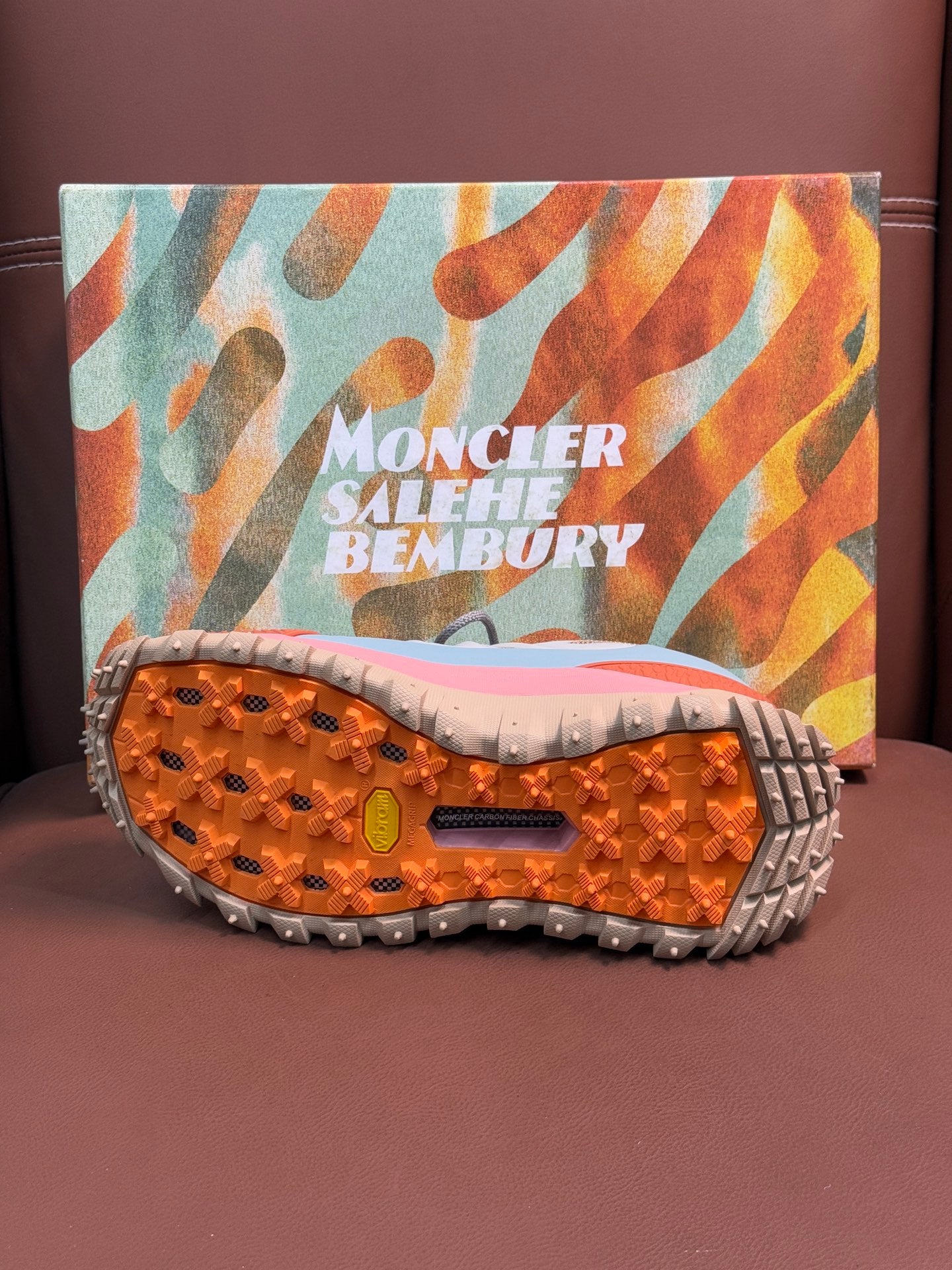 Shoe outsole with orange traction studs and rugged gray rubber sole