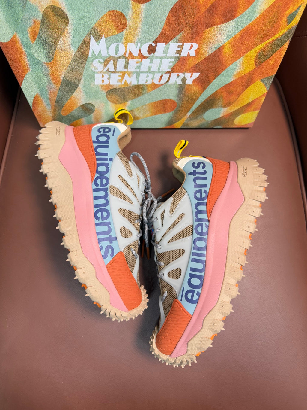 Pair of sneakers showing side panels and chunky outsoles with pink and orange