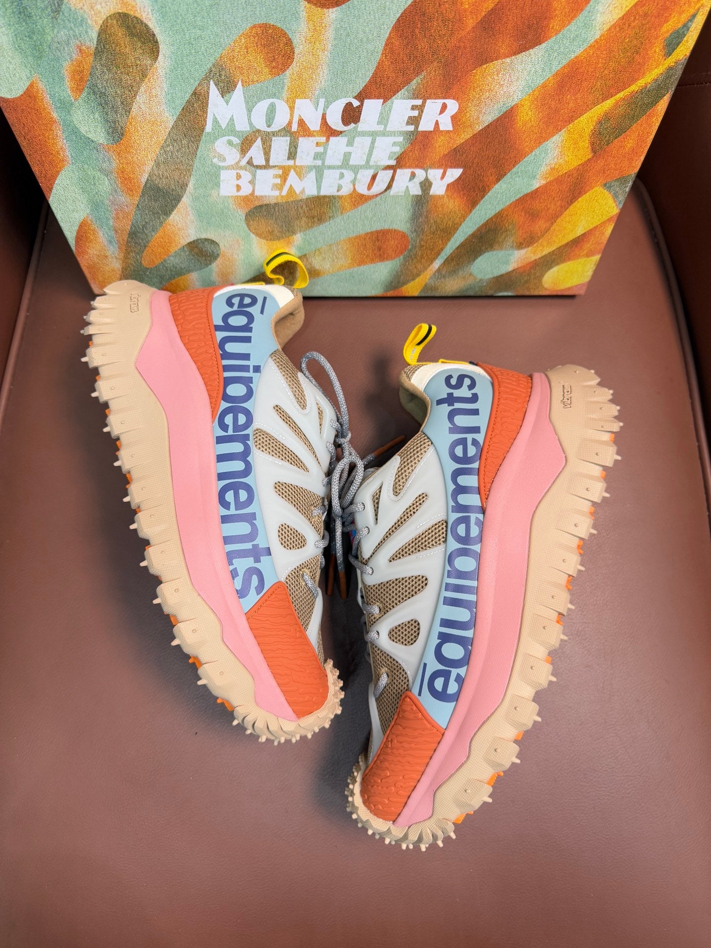 Pair of sneakers showing side panels and chunky outsoles with pink and orange