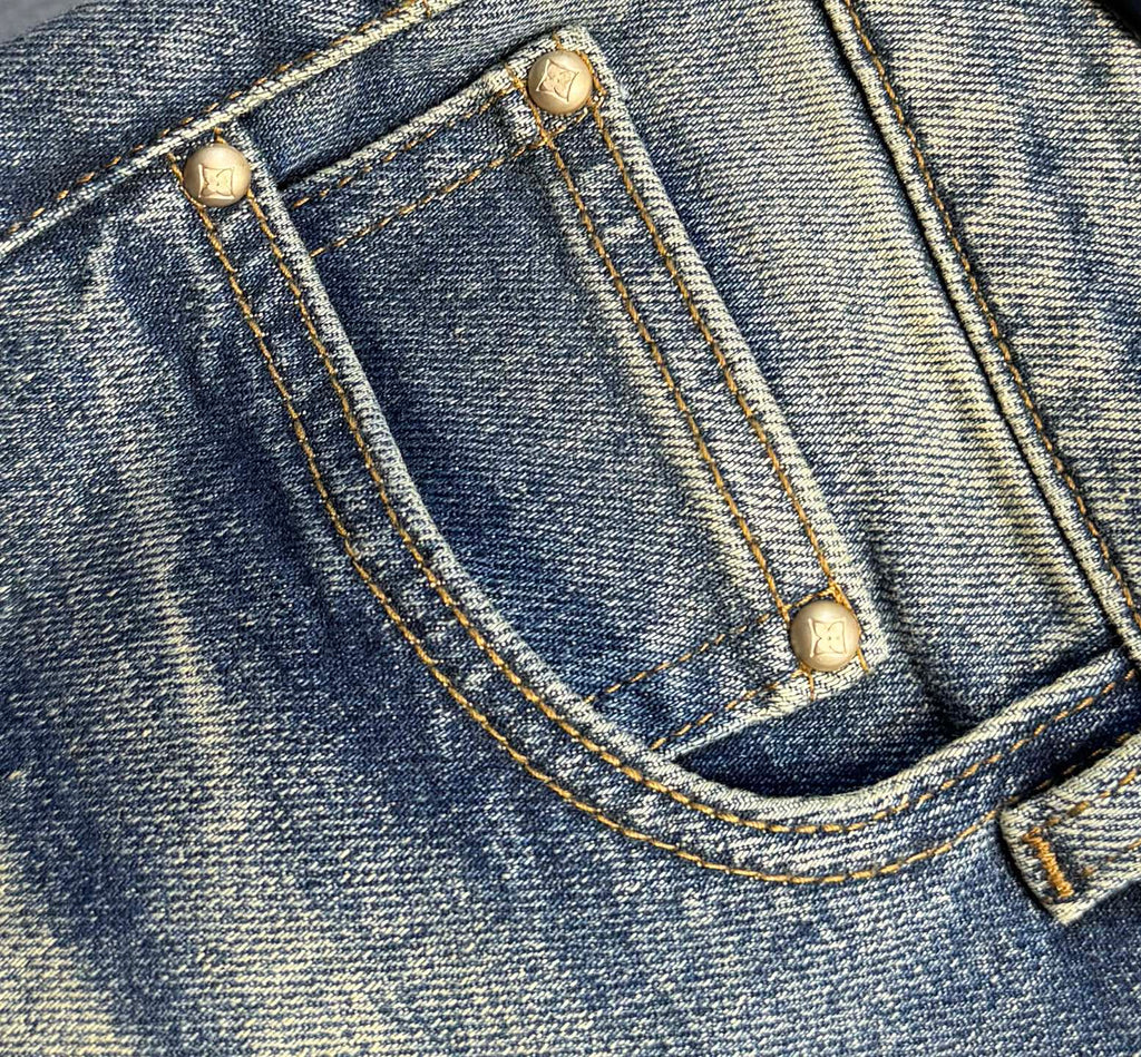 Denim jeans front pocket with gold-toned buttons and curved stitch seam