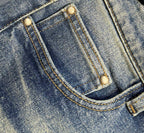 Denim jeans front pocket with gold-toned buttons and curved stitch seam
