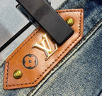 Leather coin holder detail with gold Louis Vuitton monogram on denim jeans