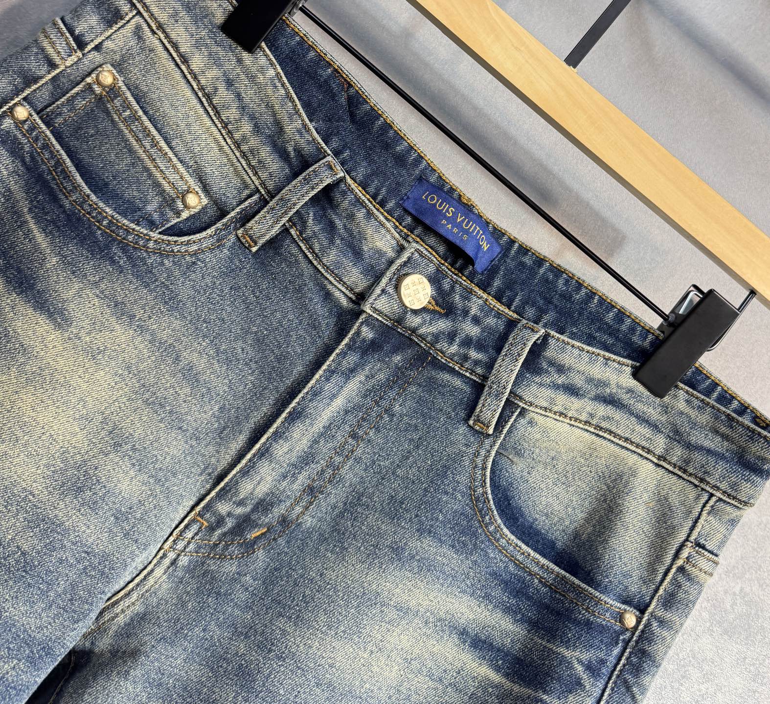 Denim jeans with visible stitching and Louis Vuitton logo waistband tag