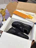 Black low-top Louis Vuitton sneakers on box, lace-up front view, textured panels.
