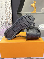 Black Louis Vuitton sneakers on orange box, tread outsole view with logo on side.
