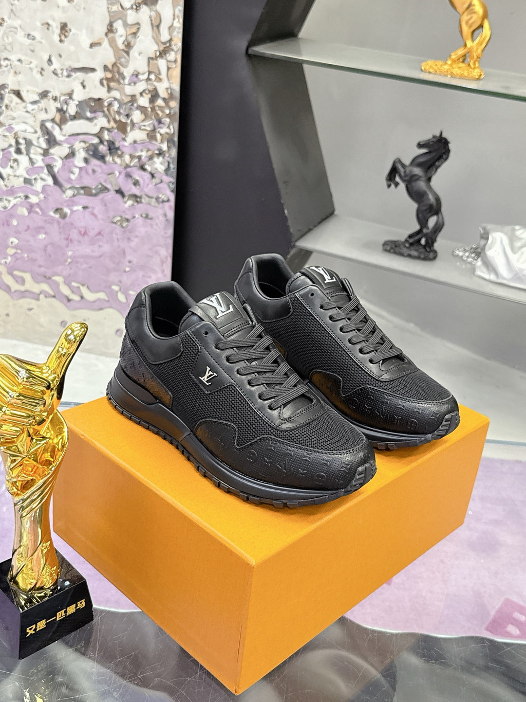 Black lace-up Louis Vuitton sneakers on orange box, side view with padded tongue.