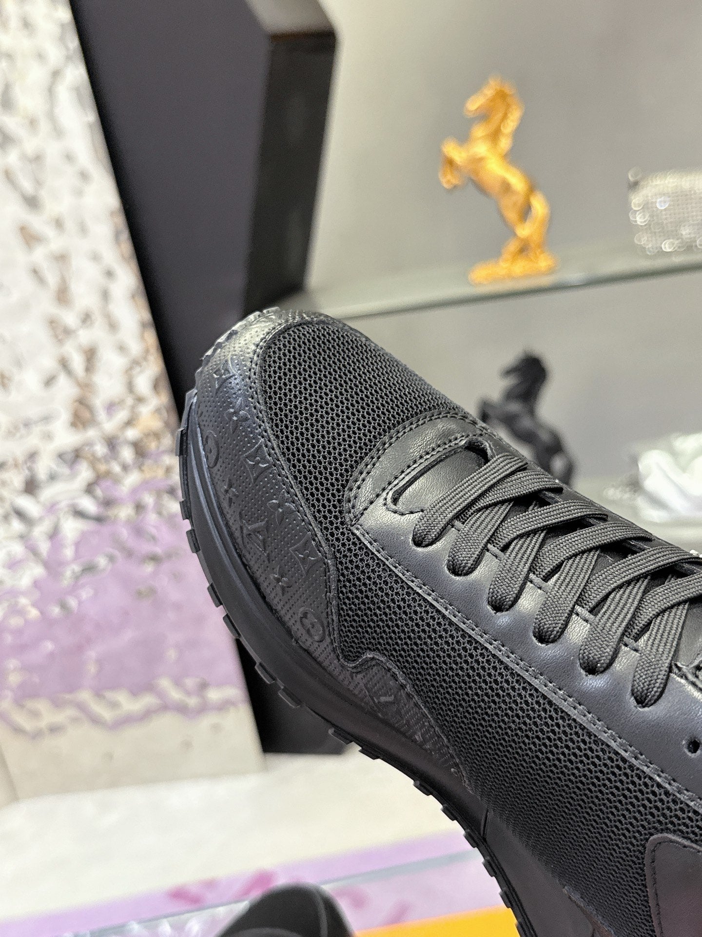 Black Louis Vuitton sneaker close-up, mesh upper and lace panel with textured toe.