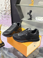 Black lace-up Louis Vuitton sneakers on orange box, angled front and side view.