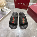 Black slide sandals with green-red stripe strap and gold G buckle, pair