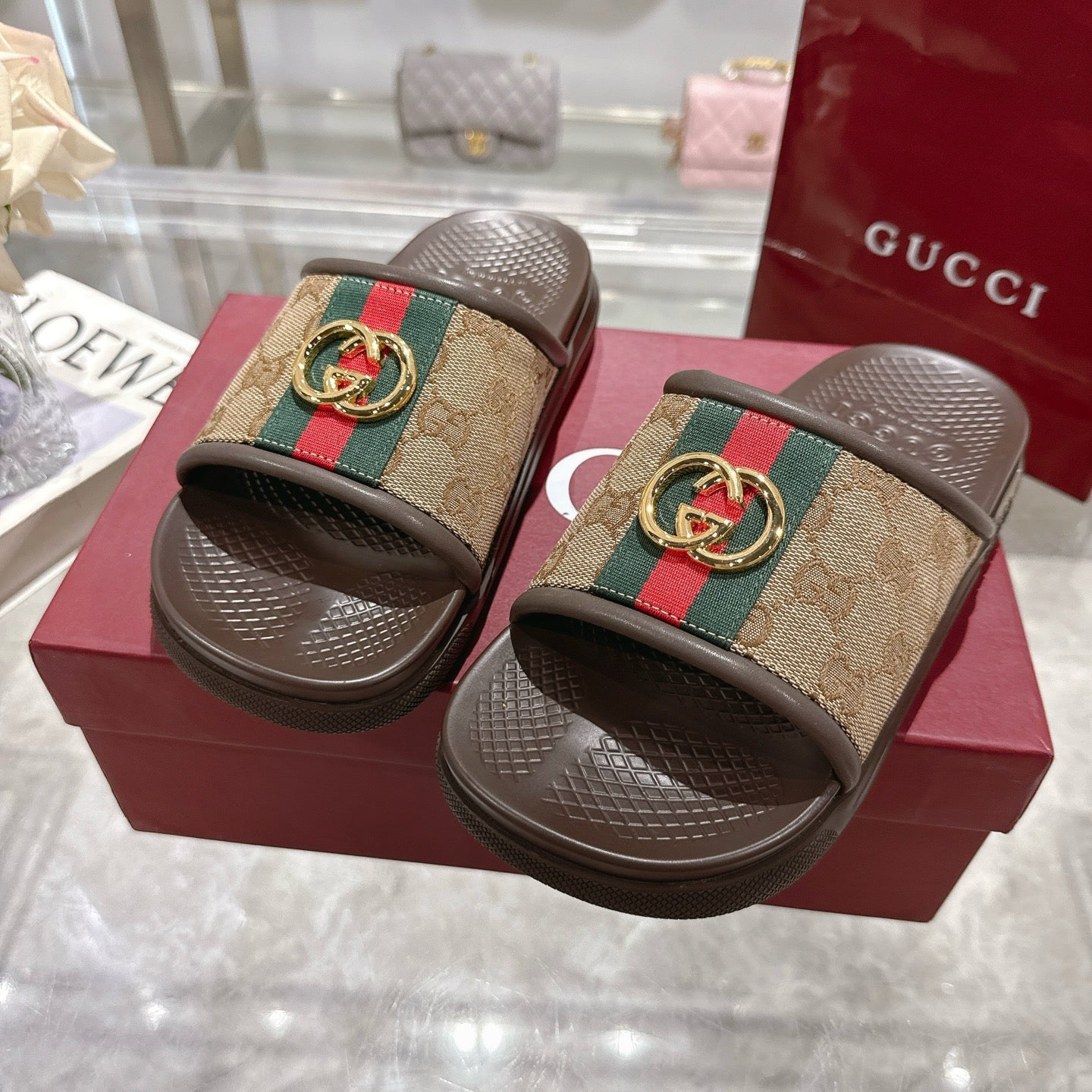 Gucci slide sandals with GG canvas straps, green/red web and gold-tone buckle, dark soles