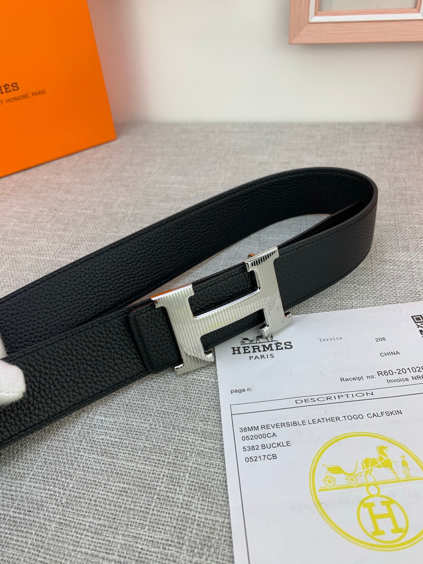 Black leather belt with silver-tone H buckle, textured strap detail